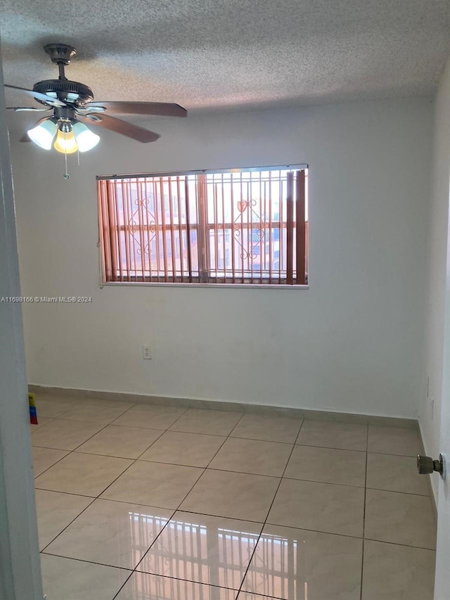 unfurnished room featuring a textured ceiling, ceiling fan, and tile patterned floors