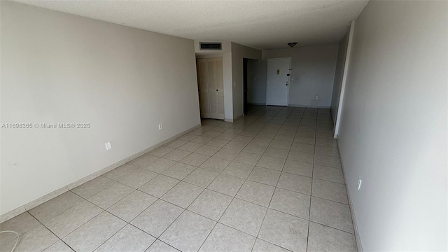 spare room featuring a textured ceiling and light tile patterned flooring