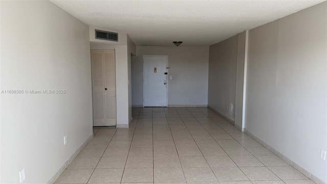 hall featuring light tile patterned flooring and a textured ceiling