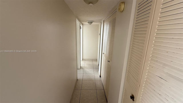 hall featuring a textured ceiling and light tile patterned flooring