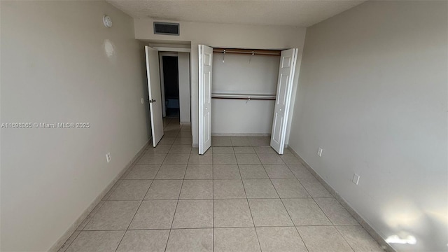 unfurnished bedroom with light tile patterned floors, a textured ceiling, and a closet