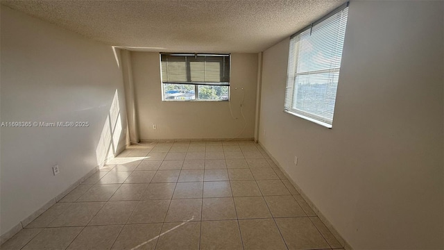 unfurnished room with light tile patterned flooring, plenty of natural light, and a textured ceiling