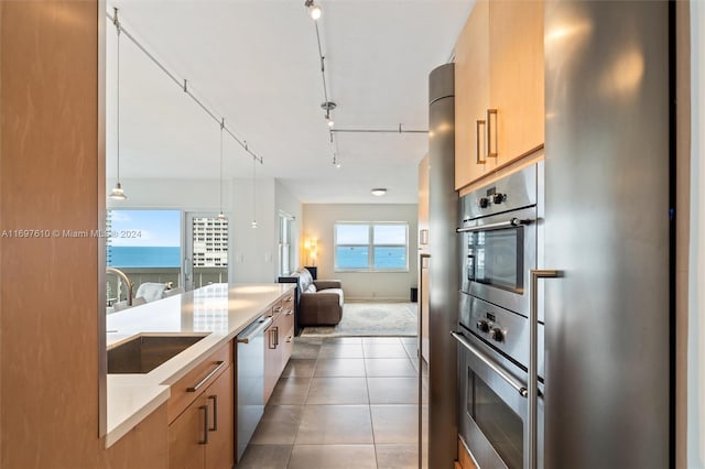 kitchen with light brown cabinets, dark tile patterned floors, a water view, and stainless steel appliances