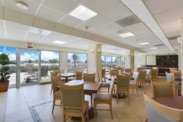 dining room with a drop ceiling and light tile patterned floors