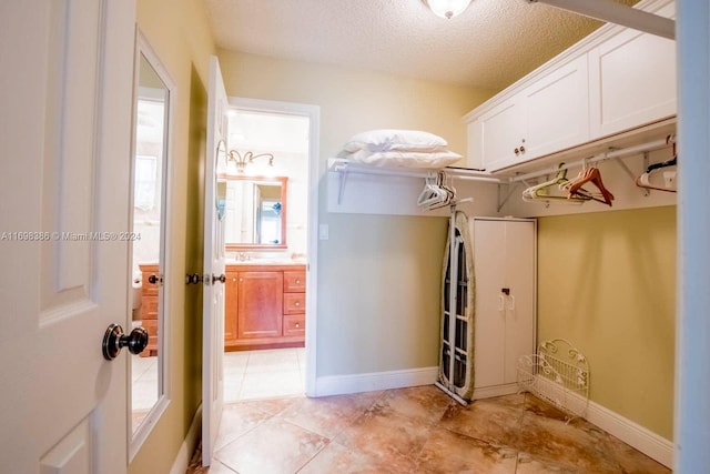 laundry area with light tile patterned floors, a textured ceiling, and sink