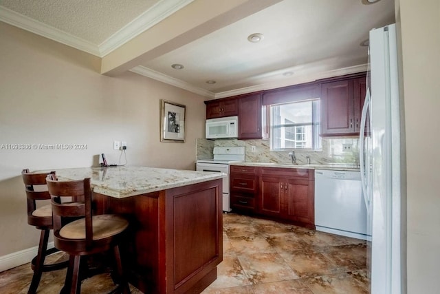 kitchen with sink, tasteful backsplash, light stone counters, white appliances, and a breakfast bar area