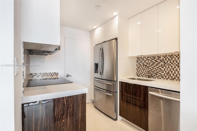 kitchen featuring tasteful backsplash, white cabinetry, sink, stainless steel appliances, and custom range hood