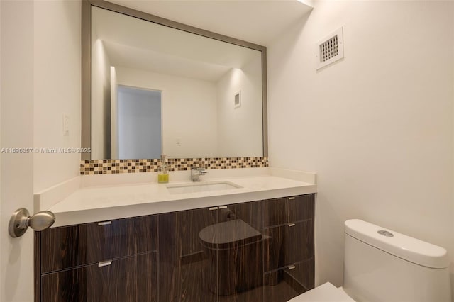 bathroom with vanity, toilet, and decorative backsplash