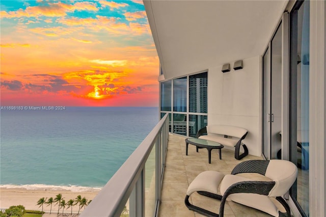 balcony at dusk featuring a water view