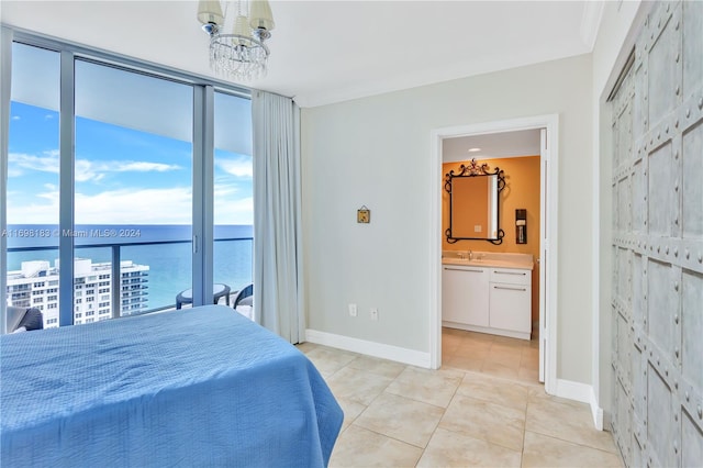 tiled bedroom with a water view, sink, connected bathroom, and a chandelier