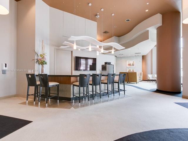 kitchen with a kitchen breakfast bar, carpet floors, and a high ceiling