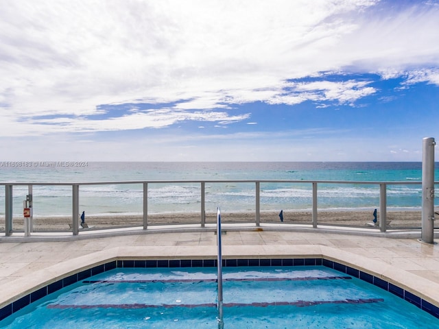 view of swimming pool with a water view and a view of the beach