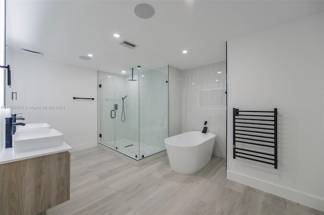 bathroom with hardwood / wood-style floors, vanity, and independent shower and bath