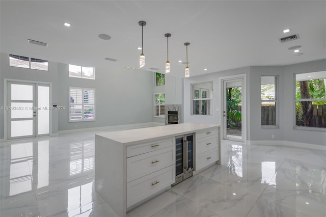 kitchen featuring plenty of natural light, white cabinetry, and beverage cooler