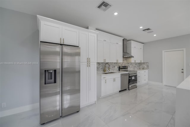 kitchen with stainless steel appliances, white cabinetry, wall chimney exhaust hood, and sink