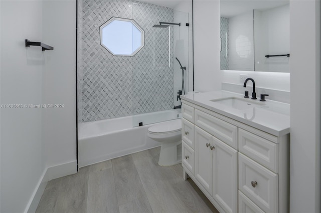 full bathroom featuring vanity, hardwood / wood-style floors, tiled shower / bath combo, and toilet