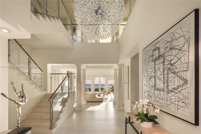 entryway with decorative columns, stairway, a high ceiling, and light wood finished floors