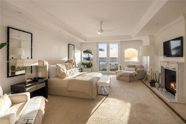 bedroom featuring access to outside, a raised ceiling, crown molding, and a glass covered fireplace