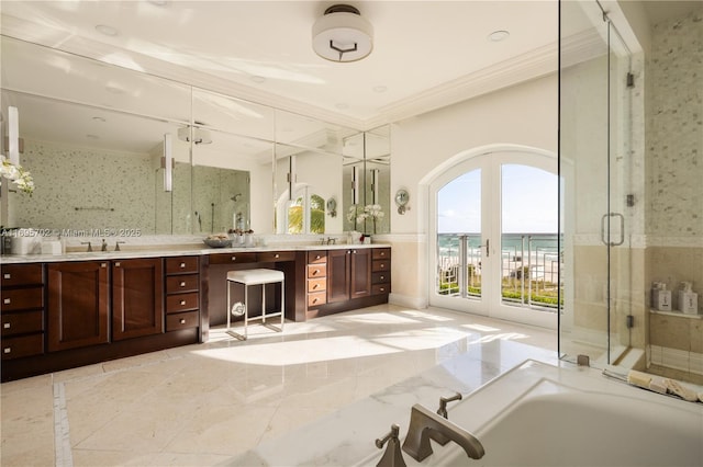 bathroom featuring double vanity, a garden tub, marble finish floor, crown molding, and a shower stall