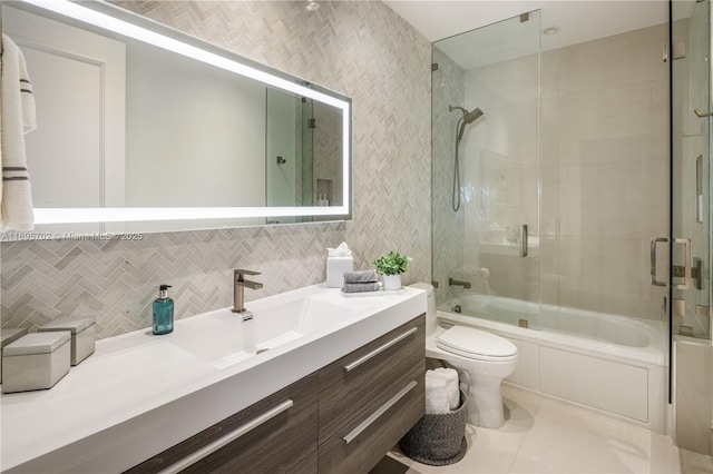 full bathroom with tasteful backsplash, bath / shower combo with glass door, toilet, tile patterned floors, and vanity