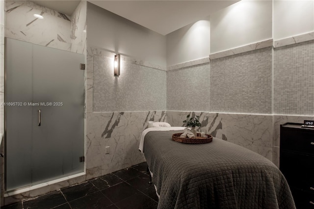 bedroom featuring marble finish floor and tile walls