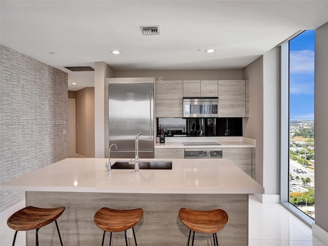 kitchen featuring sink, a breakfast bar, light tile patterned floors, and appliances with stainless steel finishes