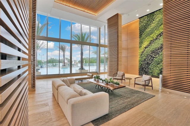 living room featuring a high ceiling, a water view, expansive windows, and light hardwood / wood-style floors