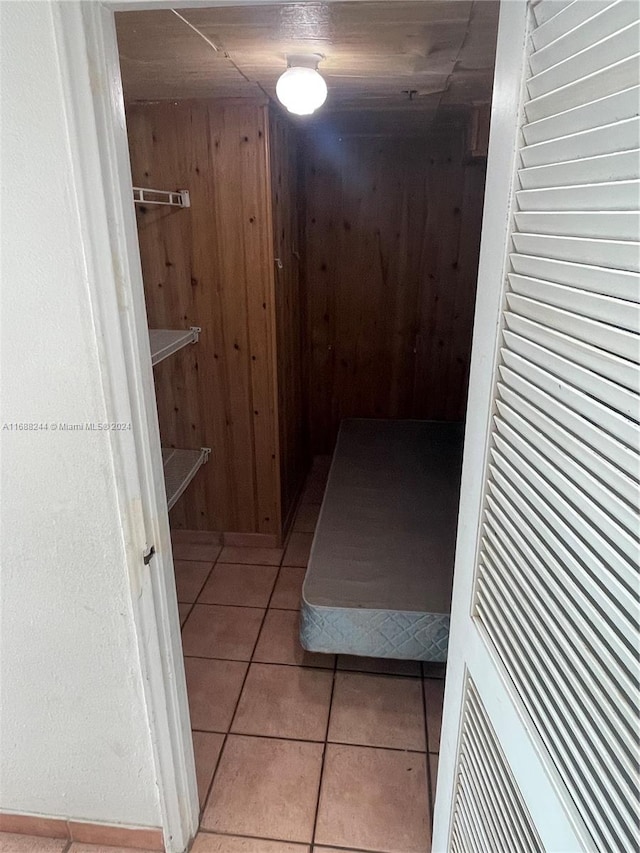 hallway featuring wooden walls and light tile patterned flooring