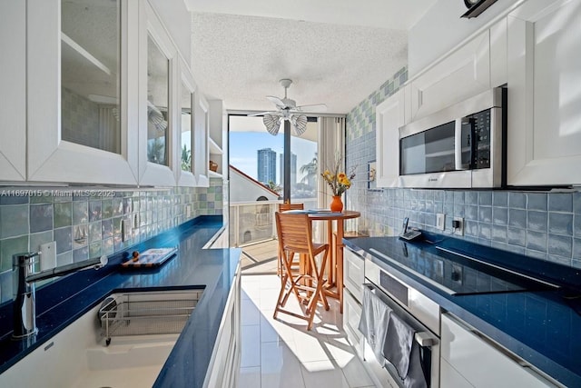 interior space with tasteful backsplash, ceiling fan, appliances with stainless steel finishes, a textured ceiling, and white cabinetry