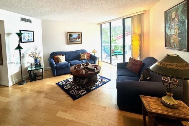 living room featuring expansive windows, a textured ceiling, and light hardwood / wood-style flooring