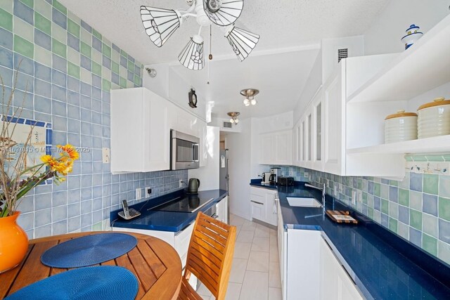 kitchen with a sink, black electric cooktop, dark countertops, and stainless steel microwave