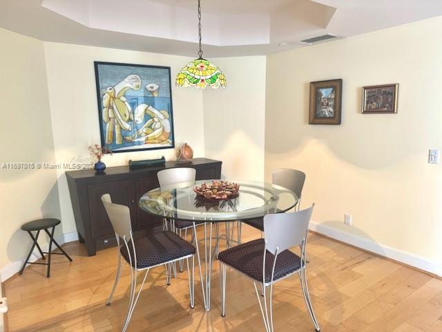 dining room featuring a raised ceiling and light wood-type flooring