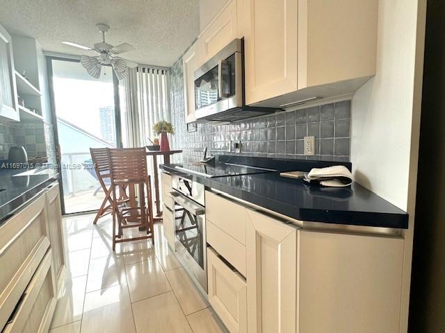 kitchen with backsplash, a textured ceiling, stainless steel appliances, light tile patterned floors, and white cabinets