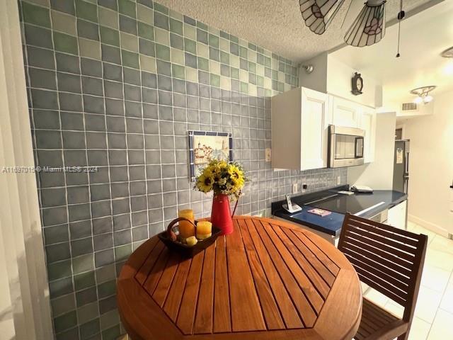 kitchen with tile patterned floors, a textured ceiling, ceiling fan, tile walls, and white cabinetry