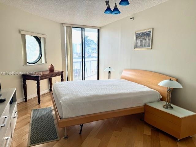 bedroom with access to exterior, ceiling fan, light hardwood / wood-style flooring, and a textured ceiling