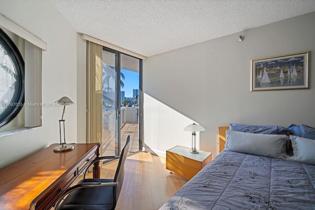 bedroom featuring a textured ceiling, wood finished floors, floor to ceiling windows, and access to exterior