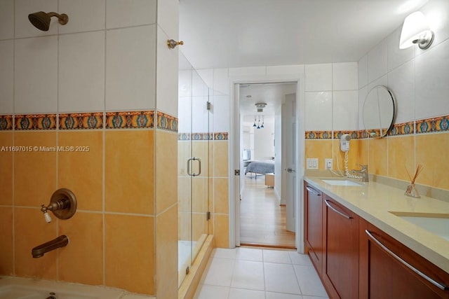 bathroom featuring double vanity, a sink, tile patterned flooring, a shower stall, and tile walls