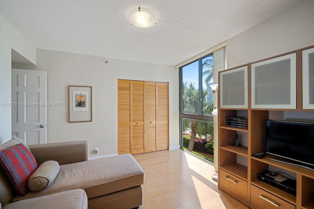 living room featuring a textured ceiling, light wood-style floors, and expansive windows