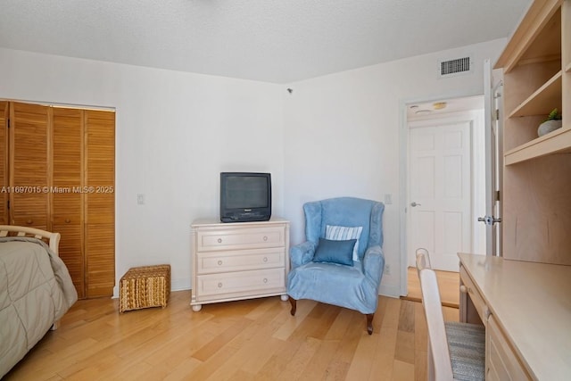 bedroom with visible vents, a textured ceiling, and light wood-style flooring