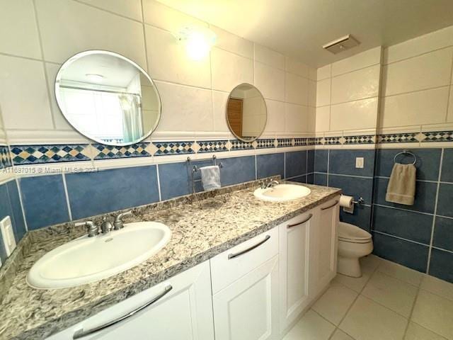 bathroom featuring tile patterned flooring, vanity, toilet, and tile walls