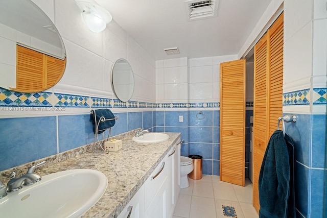 full bath with visible vents, tile walls, and a sink