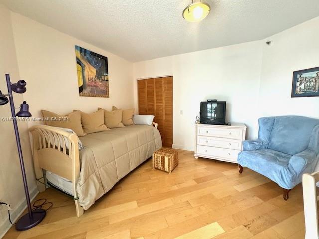 bedroom with a closet, a textured ceiling, and light hardwood / wood-style flooring