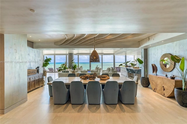 dining area with a water view, light wood-type flooring, and a wealth of natural light