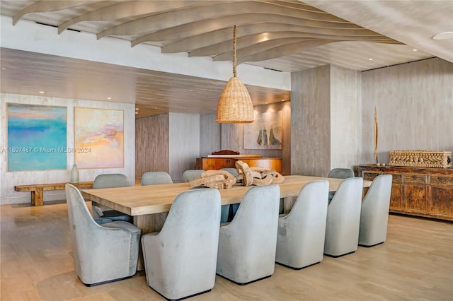 dining room featuring light wood-type flooring and wooden walls