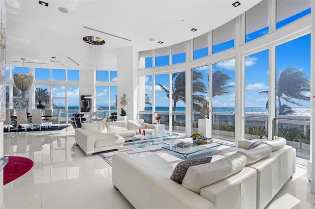 tiled living room with a water view, a towering ceiling, and a wealth of natural light