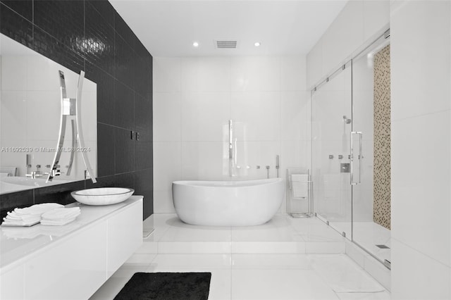 bathroom with tile patterned floors, vanity, tile walls, and plus walk in shower