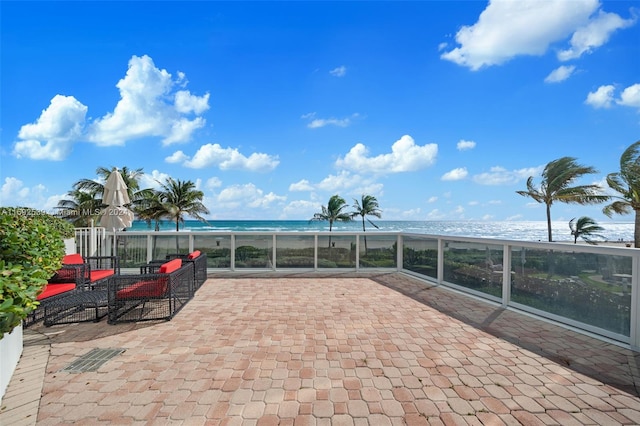 view of patio with a water view and a beach view