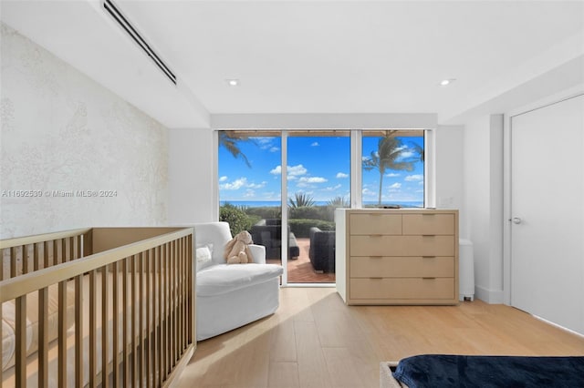 bedroom featuring multiple windows, a crib, and light wood-type flooring