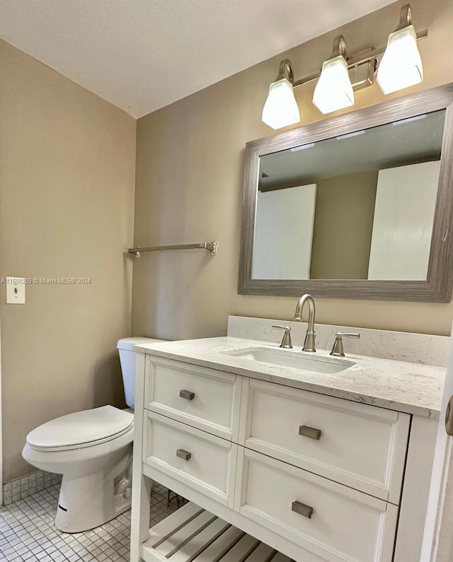 bathroom with tile patterned flooring, vanity, and toilet