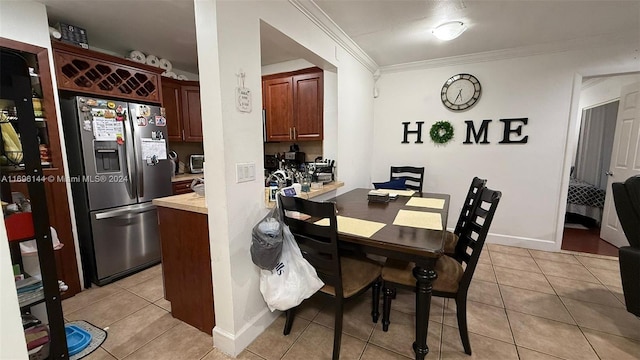 dining room featuring light tile patterned floors and crown molding